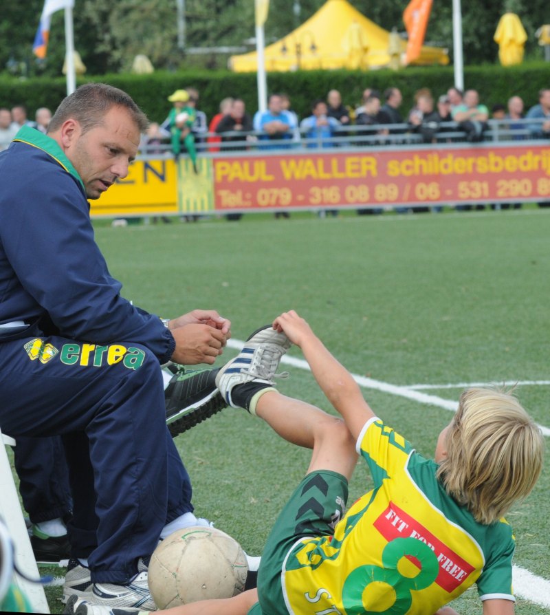 Deze jonge supporter lijkt aan de trainer te vragen of hij wel de goede schoenen voor dit (kunstgras)veld aan heeft